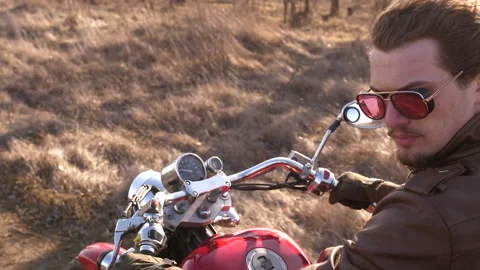 Slow motion of cool young biker, on red chopper, expressive looking back Stock Footage 151837792