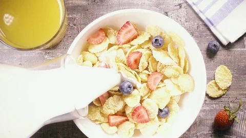 Slow motion corn flakes with berries pour liquid top view Stock Footage 93872641