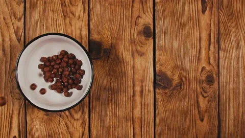 Slow motion of corn flakes falling into white bowl on wooden table Stock Footage 144528039