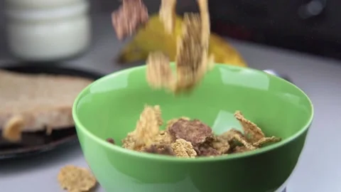 Slow motion of cornflakes falling into a green bowl. Healthy food concept 動画素材 238011565