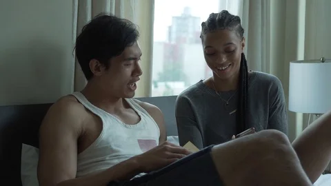 Slow motion of couple laughing while looking at smart phone while sitting in bed Vídeo Stock 114878534