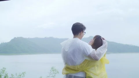 Slow motion - couple using romantic time playing rain while standing near lake. Stock Footage 101266527
