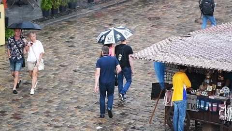 Slow motion of couple walking under rain umbrella in Lviv old town market square Vídeos de archivo 112585191