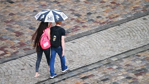 Slow motion of couple walking under rain umbrella in Lviv old town market square Vídeos de archivo 112585399