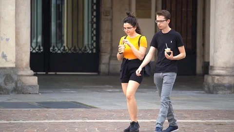 Slow motion of a couple is walking while eating an ice cream Stock Footage 111877566