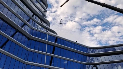 Slow motion of crane hoisting glass panel into building gap Stock Footage 337359389
