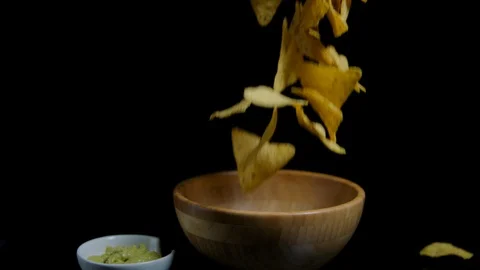 Slow motion Crispy nachos is falling into the wooden bawl. Black background Stock Footage 92563382