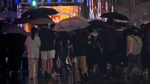 Slow motion of crowd with umbrellas walking through rain at night Hakata Station Stock Footage 322182426