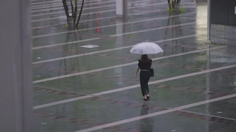 Slow motion crowd walking across rainy plaza with umbrellas near Hakata Station Stock Footage 321758793
