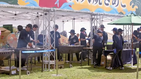 Slow motion of crowd watching barbecue chefs grilling fish at outdoor festival Stock Footage 321419243