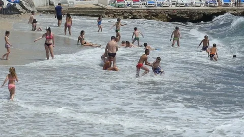 Slow motion, crowded beach, people enjoying on a stormy sea Stock Footage 79882810