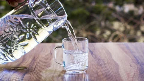 Slow Motion of Crystal Clear Water Pouring from Pitcher into Glass Cup, 4K Видео 330799747