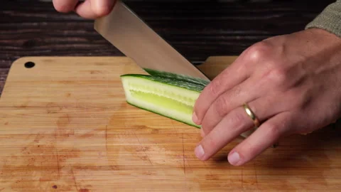 Slow motion cucumber half being sliced on wooden board Stock Footage 301451304