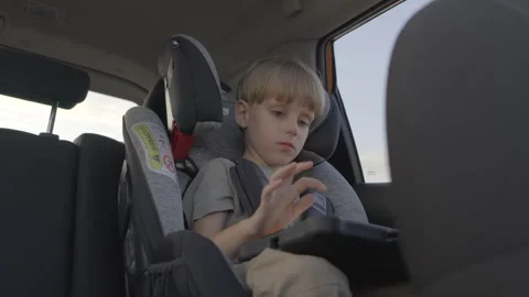 Slow motion. Cute 5 years old boy plays tablet piano during a trip in a car. Stock Footage 280544165