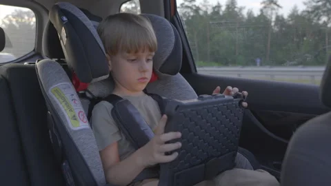 Slow motion. Cute 5 years old boy plays tablet during a trip in a car. 库存影片 280544201
