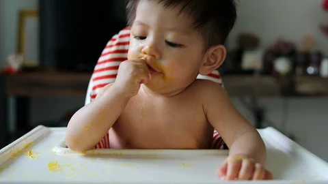 Slow-motion, cute baby using finger hand in mouth with food puree dirty on face Stock Footage 88320756
