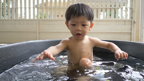 Slow motion, cute child playing toy in small water pool bath time Stock Footage 94653432