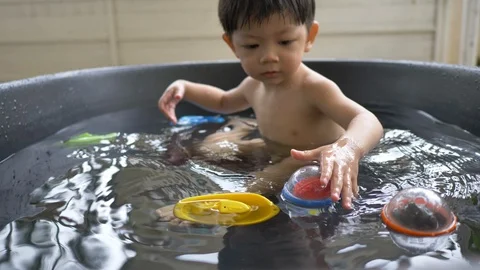 Slow motion, cute child playing ball in small water pool bath time Stock Footage 94654111