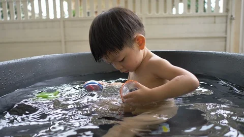 Slow motion, cute child playing toy in small water pool bath time Stock Footage 109501437