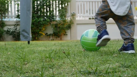 Slow-motion, cute child toddle falling on green grass playing ball Stock Footage 87543149