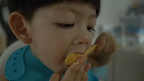 Slow motion cute child using spoon in eating time Stock Footage 94654956