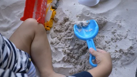 Slow motion cute child using shovel toy playing sand on the beach Stock Footage 99320640