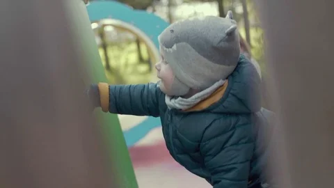 SLOW MOTION Cute little active European boy playing on the playground in cool Stock Footage 75736969