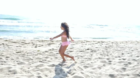 Slow motion of a cute little girl in swimsuit playing on the sea beach Stock Footage