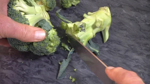 Slow motion: Cutting the stalk off a piece of broccoli. Video stock 96744488