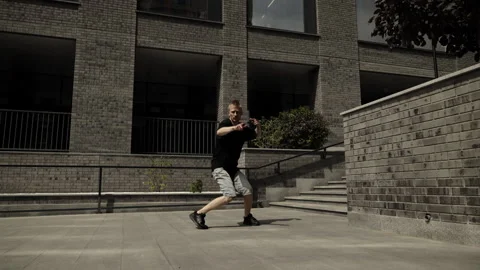 Slow motion dancing. A man dances against the backdrop of a gray brick building. Stock Footage 252190943