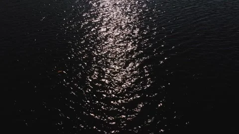Slow-motion of dark and dramatic body of water with the sun shining bright creat Stock Footage 289585679