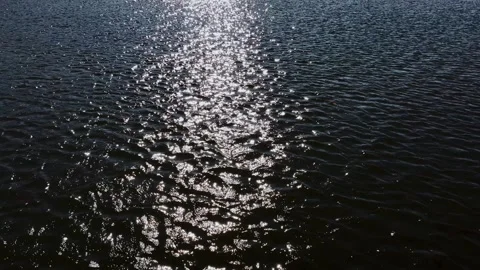 Slow-motion of dark and dramatic body of water with the sun shining bright creat Stock Footage 289592758