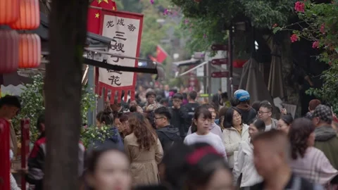 Slow motion of dense pedestrian crowd moving through narrow red lantern alley Stock Footage 315582983