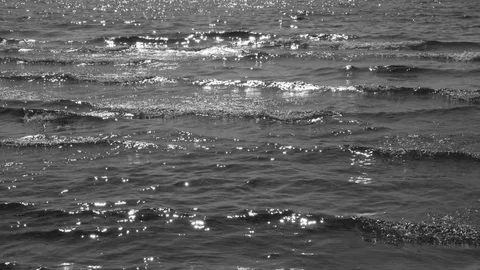 Slow motion detail of small sparkling and breaking sunlit waves. B&W. Stock Footage