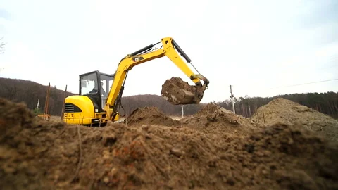 Slow motion of a digger digging a pit and throwing dirt. Close-up of a excavator Video stock 104932608