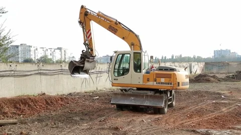 Slow motion of a digger digging a pit and throwing dirt. Stock Footage 148630399