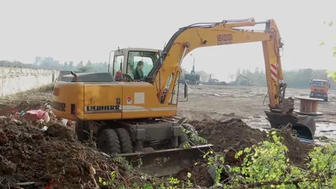 Slow motion of a digger digging a pit and throwing dirt. Stock Footage 148631972
