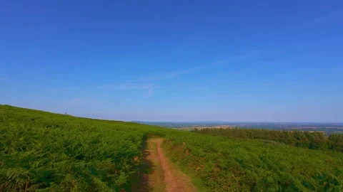 Slow motion dirt pathway through green hill field under blue sky Stock Footage 340441859