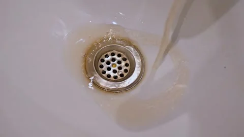 Slow Motion of Dirty Rusty Brown Water Flowing into White Ceramic Sink Drai.. Video stock 331286062