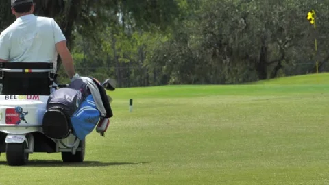 Slow motion of a disabled golfer rolling in a wheelchair on a golf course Stock Footage 158744720