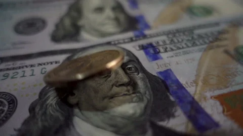 Slow motion dollar coin rotates on one hundred dollar bills. Video stock 112348762
