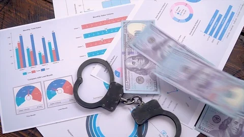 Slow motion dollars scattered on table with handcuffs, graphs and sales charts Stock Footage 127530688