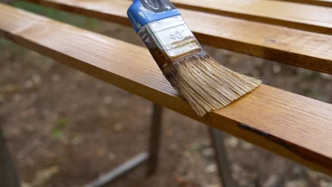 Slow motion dolly shot of a brush slowly painting a wood piece. Stock Footage 113068641