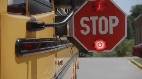 Slow motion dolly shot of school bus stop sign opening and flashing Stock Footage