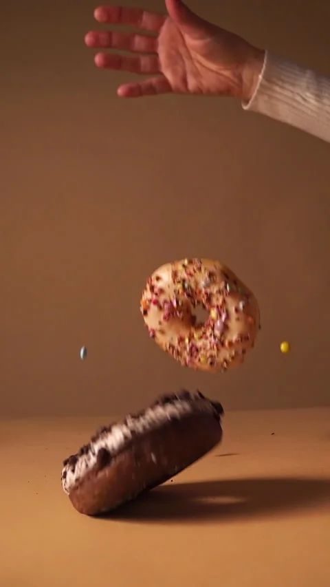 Slow Motion Donuts Falling with Hand and Flying Candy Pieces Stock Footage 331232326