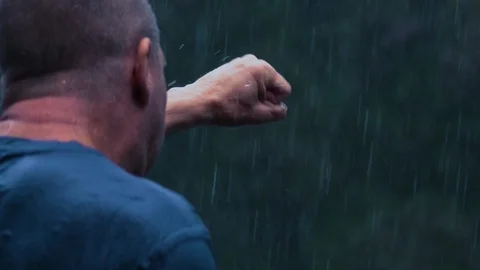 Slow motion: A drenched man shadowboxes in the pouring rain in a thunderstorm Video stock 93161460