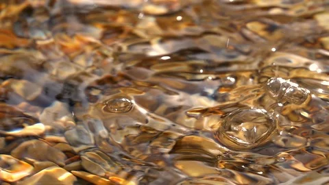Slow motion of dripping on shallow pure water with brown pebble bottom close up. Stock Footage 98096460