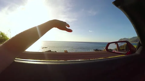 SLOW MOTION: Driving along the beach at sunset, hand waving in the summer wind Stock Footage 63385516