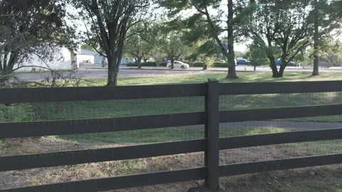 Slow motion drone flight along fence line into sunlit trees Stock Footage 346731984