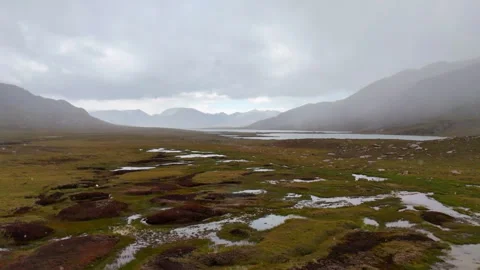 Slow-motion drone flight leftward through snow toward lake in Kyrgyzstan. Stock Footage 316053711